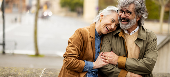Couple standing embracing each other on a stone walking bridge over a river