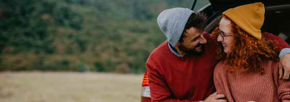 Couple sitting on the back of a vehicle embracing each other.